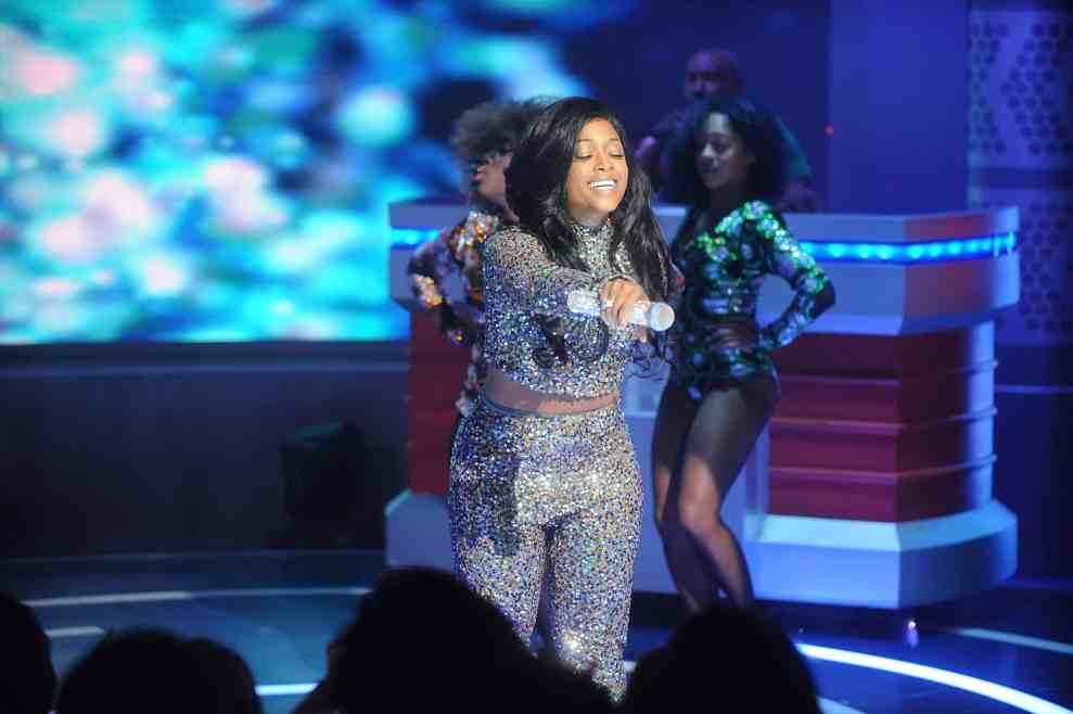 Trina performing in sparkle top and pants holding out microphone to audience