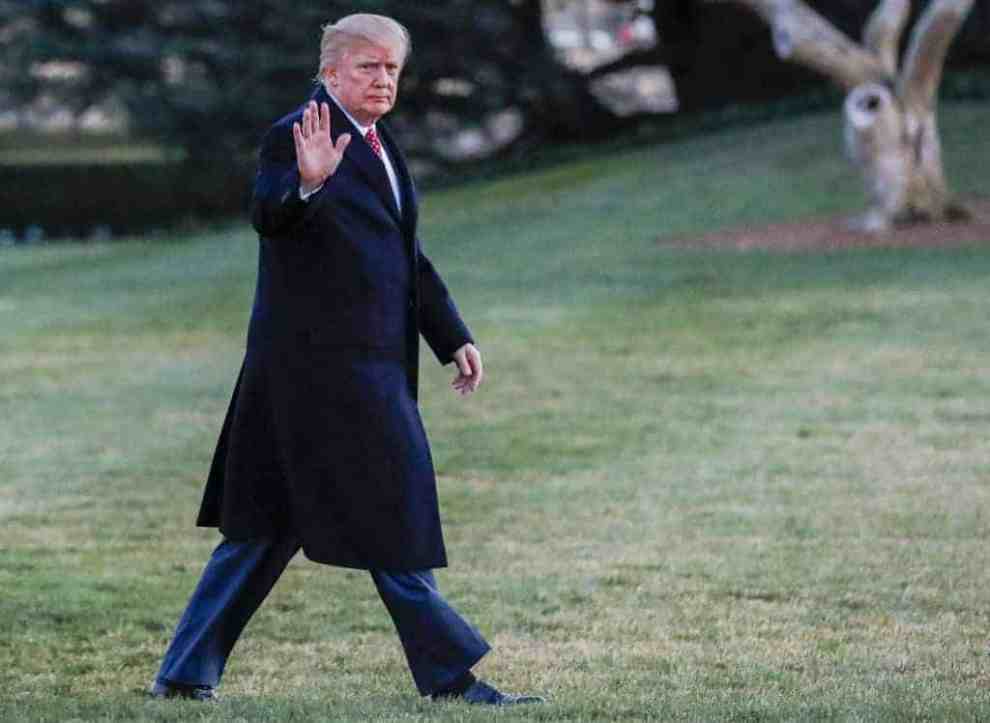 Donald Trump in trench coat and suit waving