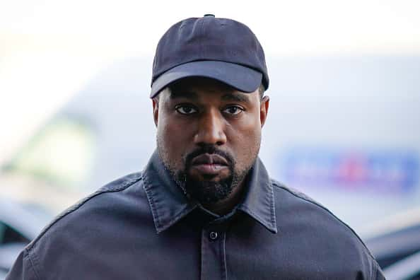 Kanye West in black baseball cap and black button down shirt