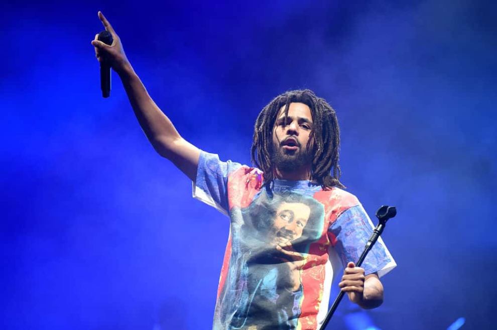 J.Cole on stage holding a microphone
